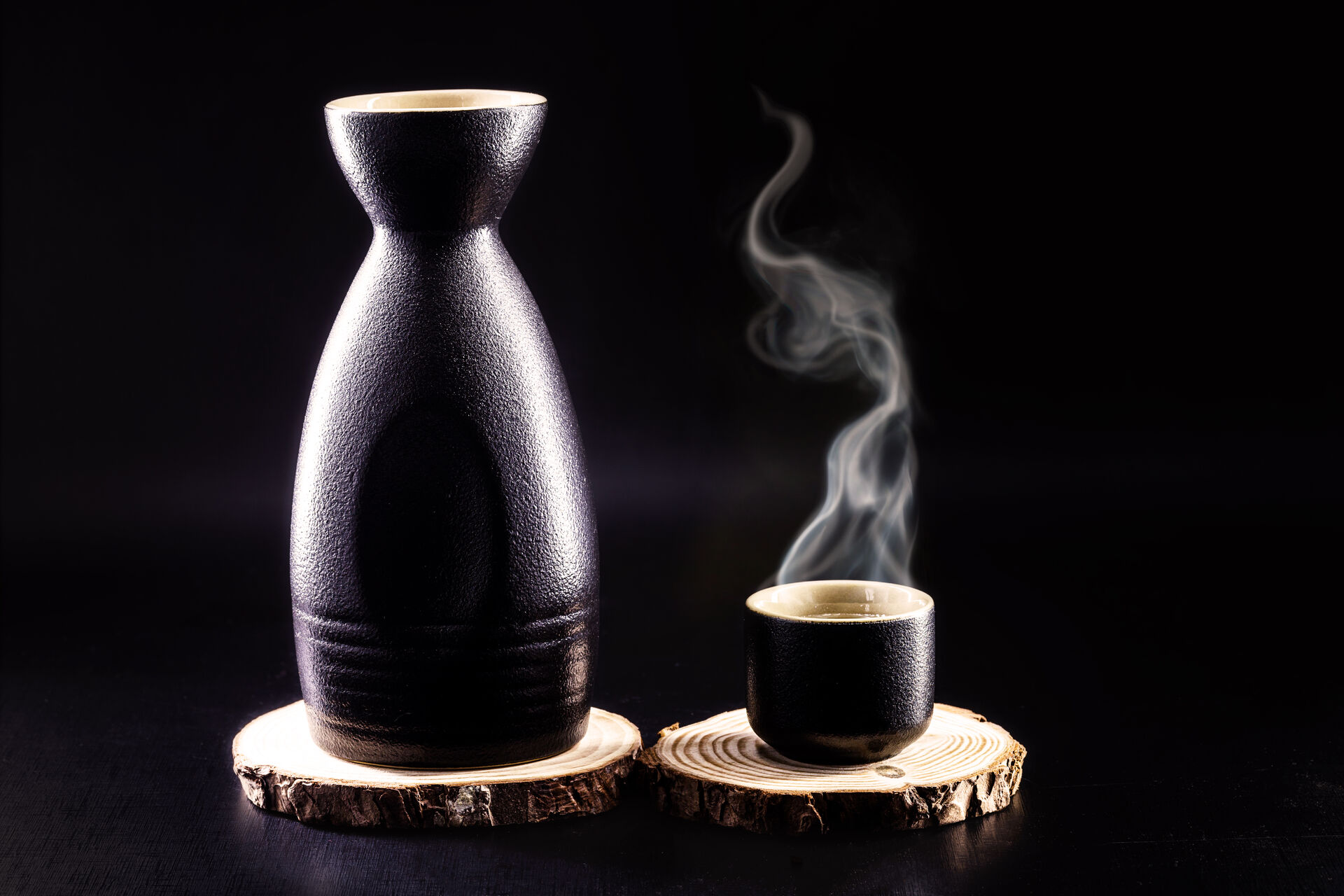 bottle-and-glass-of-sake-hot-japanese-alcoholic-drink-with-steam-black-background-and-copy-space